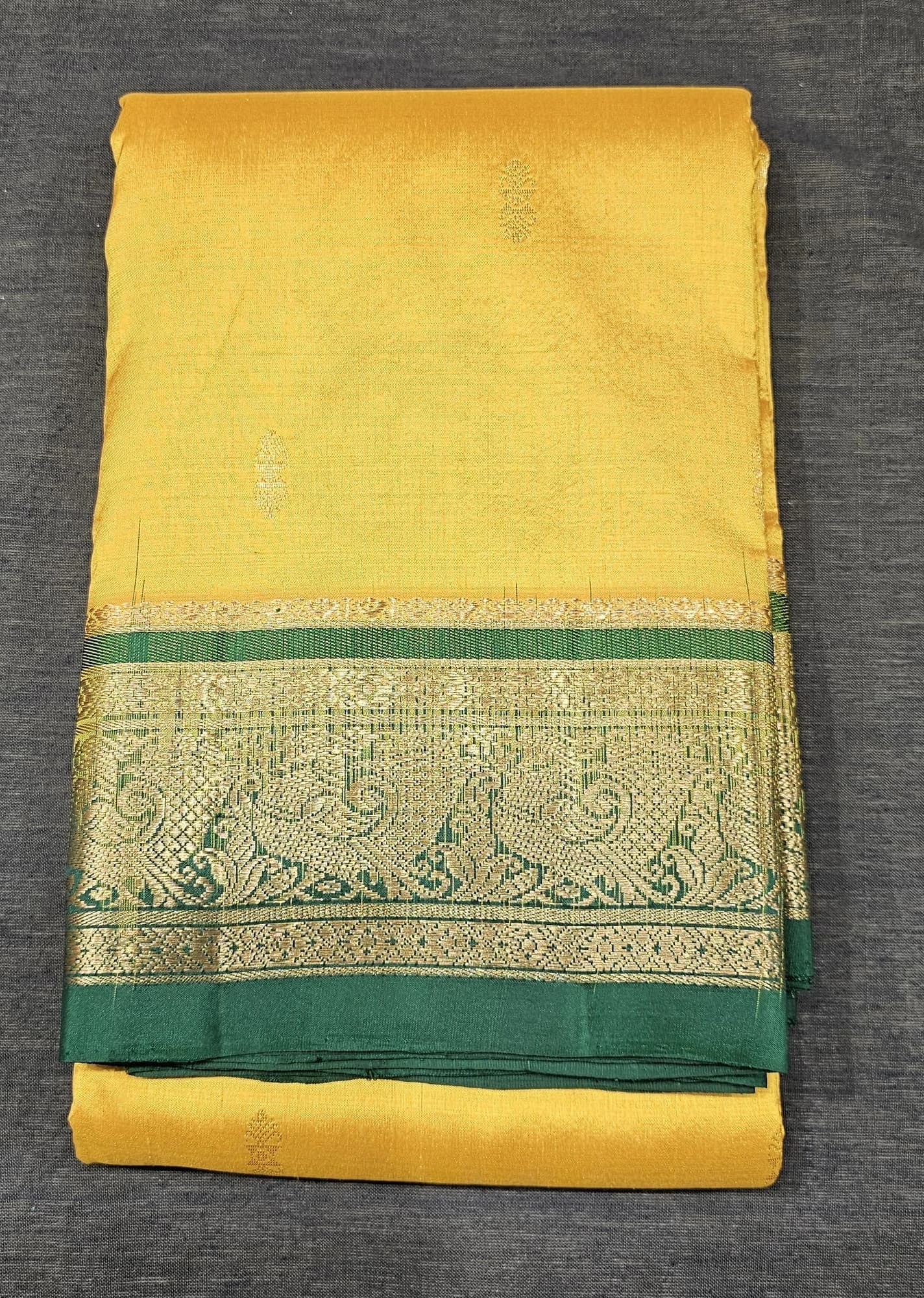 Mustard w Green Dharmavaram Silk Saree, folded, displaying a rich green border with gold zari.