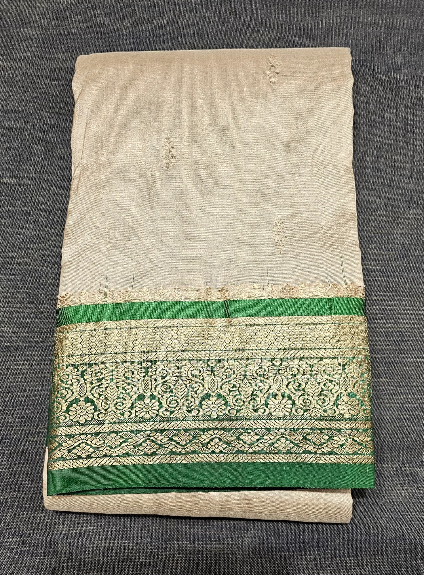 Sandal w Green Dharmavaram Silk Saree with elaborate gold zari border, folded on a dark surface.