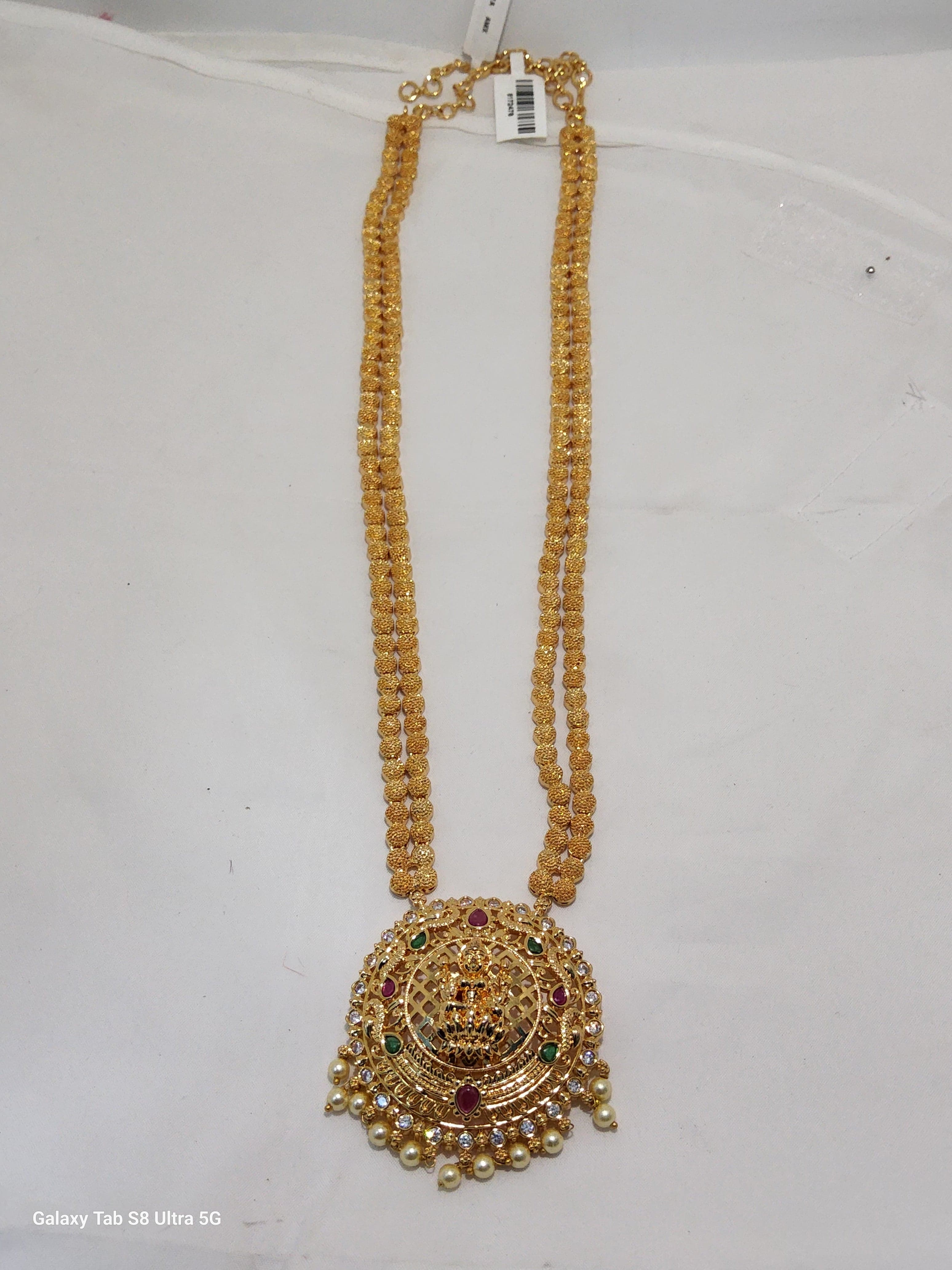 Close-up: Lakshmi dollar chain with pink, green stones & pearls. Imitation necklace detail.