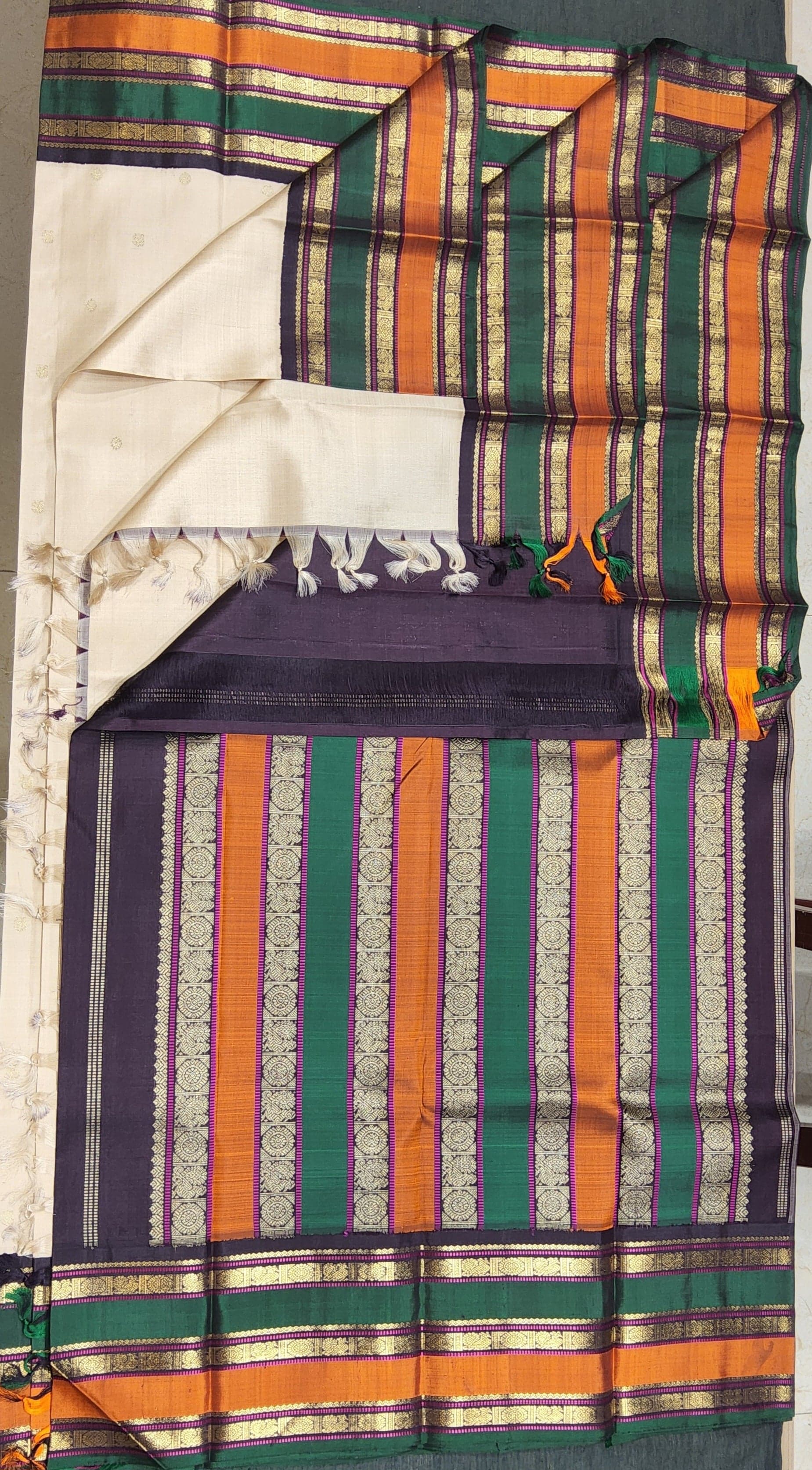 Kanchipuram silk saree close up. Half white body with multi colored border and 2G gold zari work.