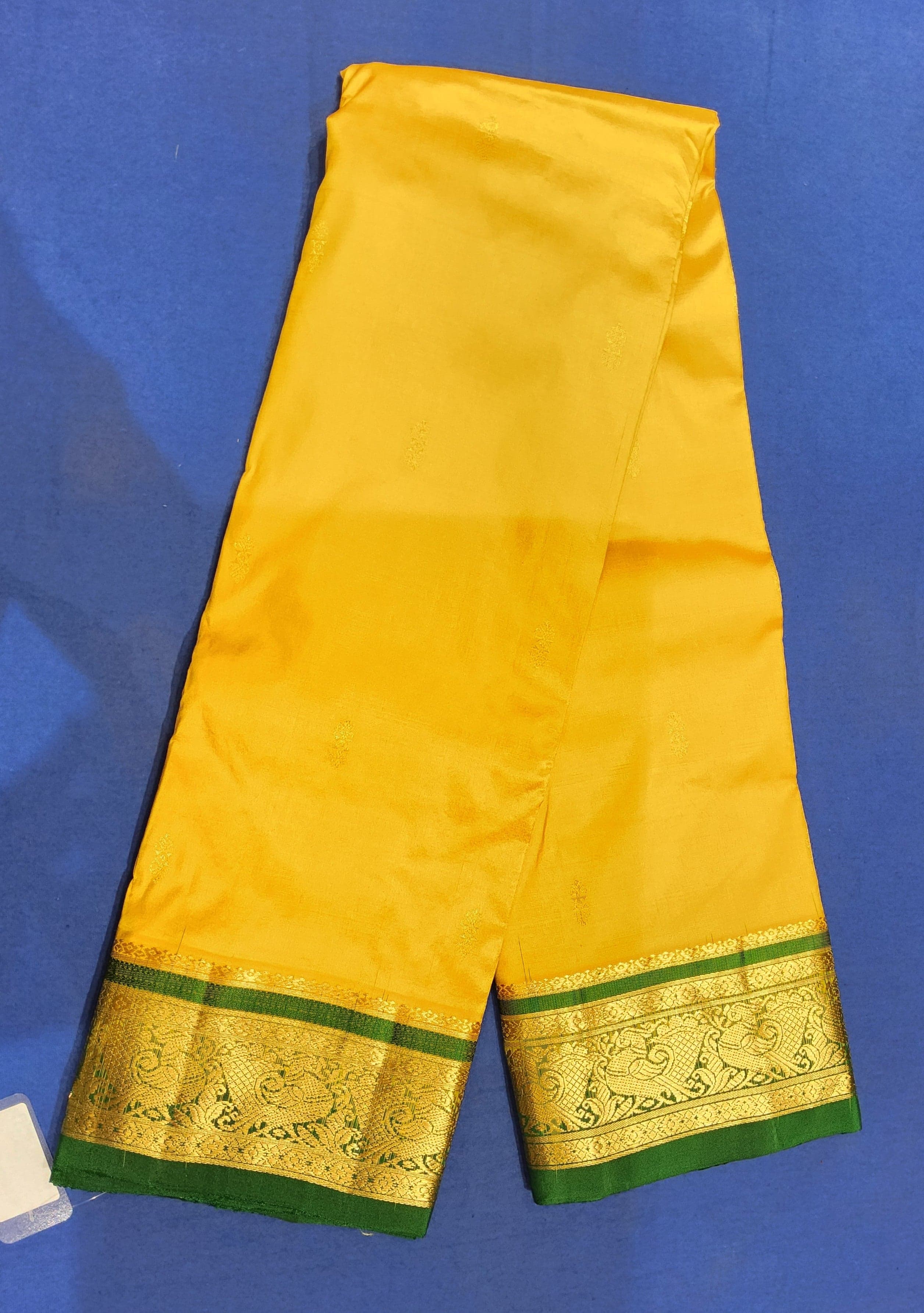 Close-up of gold zari peacock and paisley motifs on green border of authentic silk Dharmavaram saree.