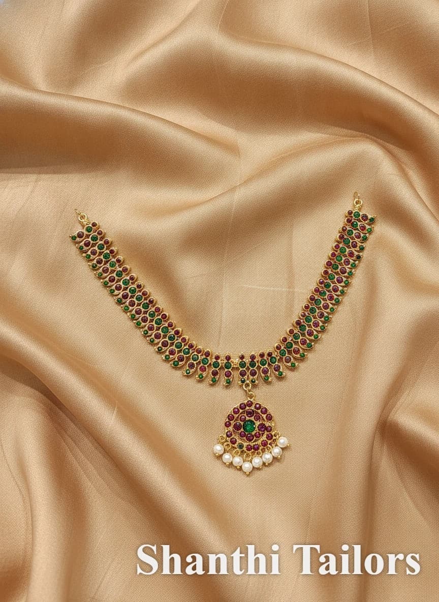 Surul Mango Necklace, imitation jewellery with red & green stones and pearl drops on a golden fabric.