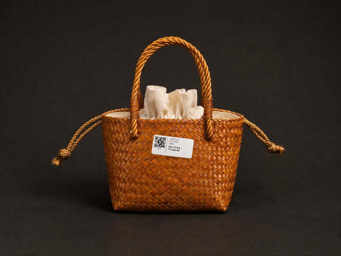 Shanthitailors' brown woven palm leaf (ஓலை) bag for Nattuvangam, with braided handle and drawstring. Price tag visible.