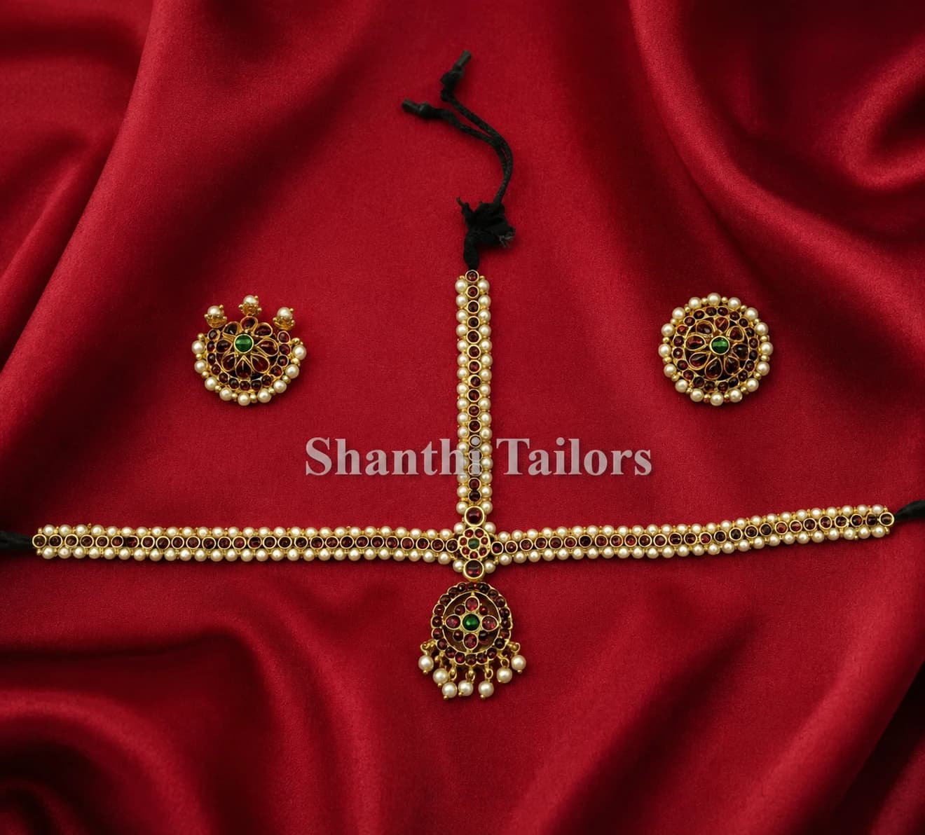 Thin headset imitation jewellery set, maang tikka with pearls & red/green stones, and two round side pieces.
