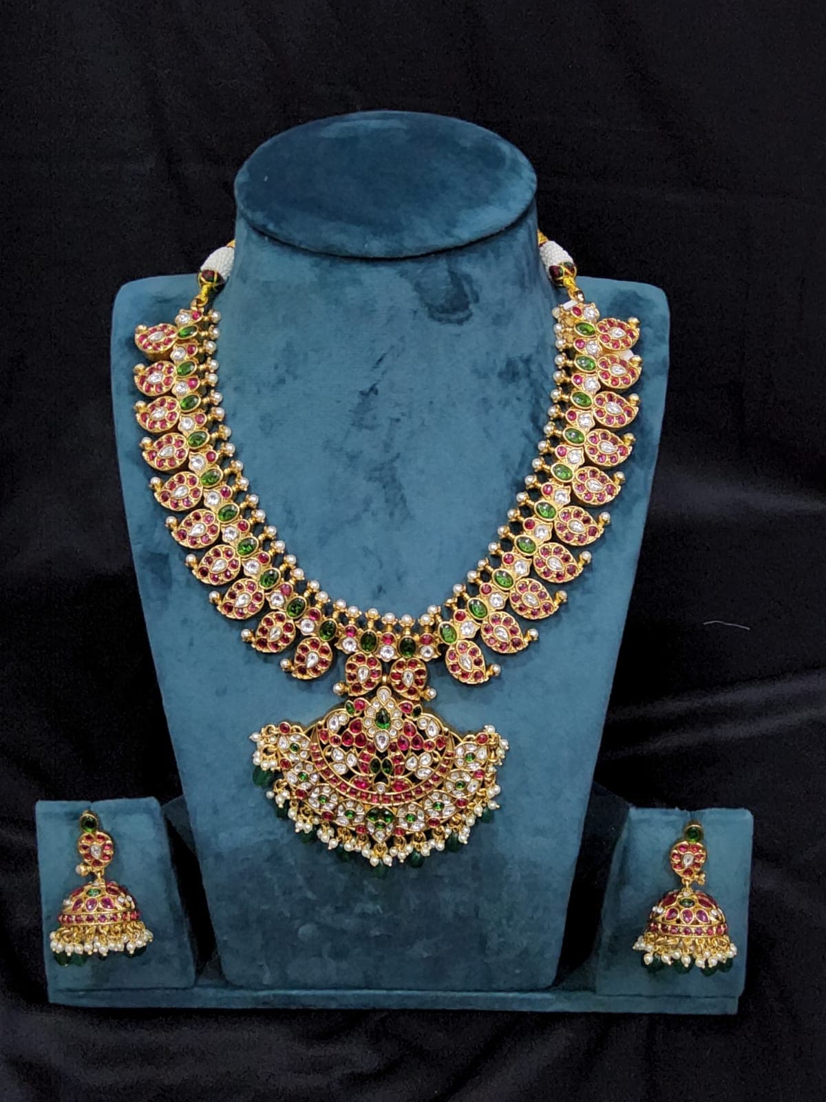 Close-up of Antique Mango Malai Set jhumkis: intricate copper design with vibrant white, green, red stones.