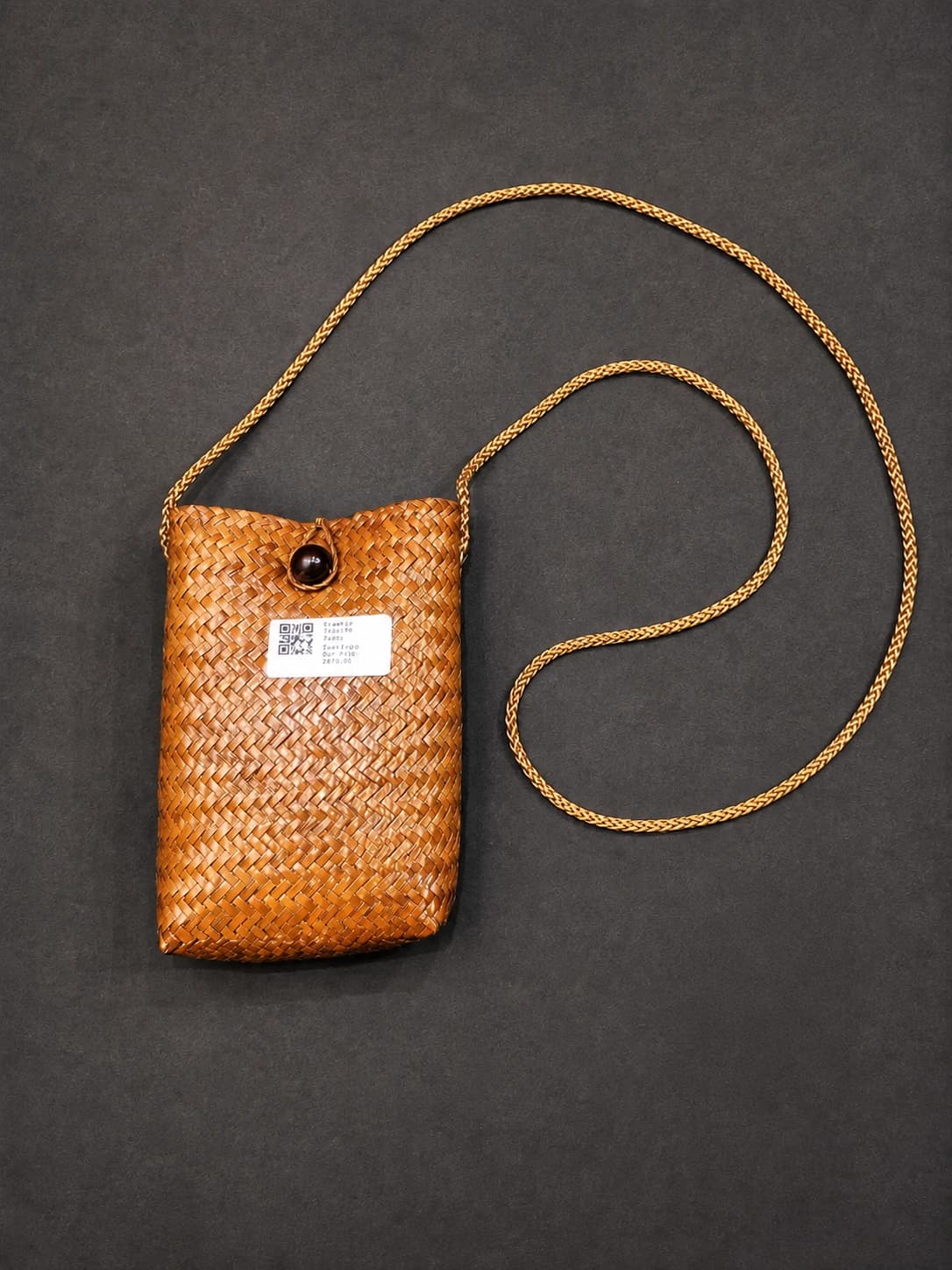 Palm Leaf (ஓலை) Bag for Nattuvangam, woven brown, with a golden strap & dark button closure on a dark background.