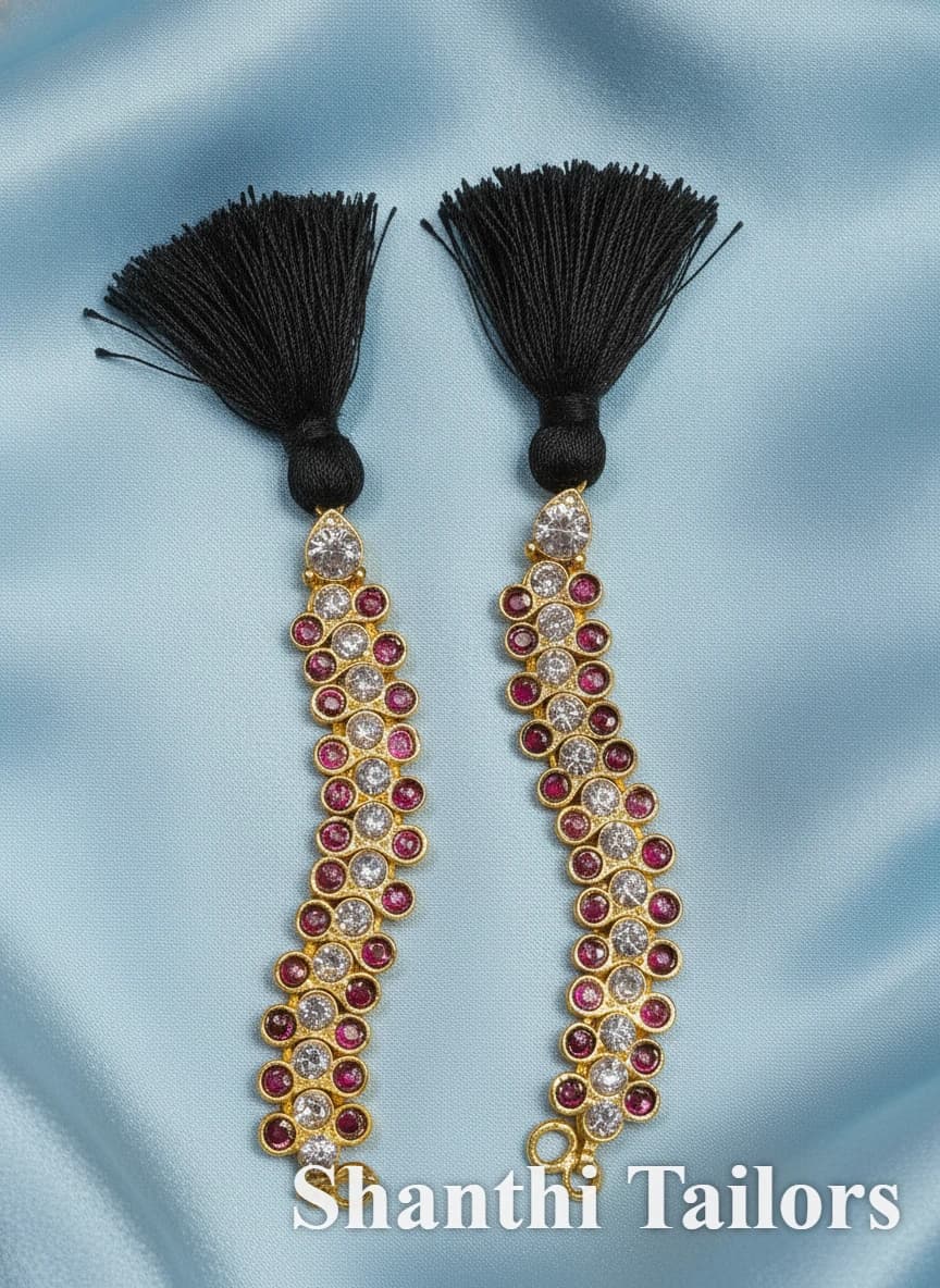 Traditional Copper Mattal (81291SP) with black tassels, clear & red stones on gold-toned base, on blue fabric.
