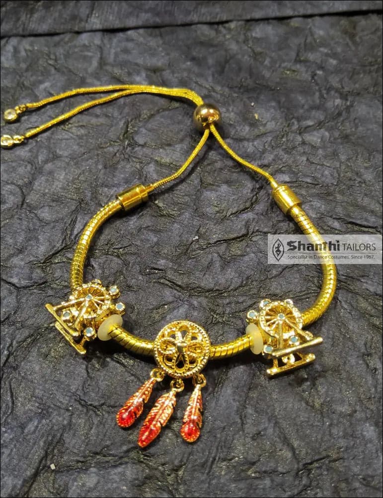 Close-up: Golden Feather Drops Bracelet with vibrant red feather details. Adjustable design.