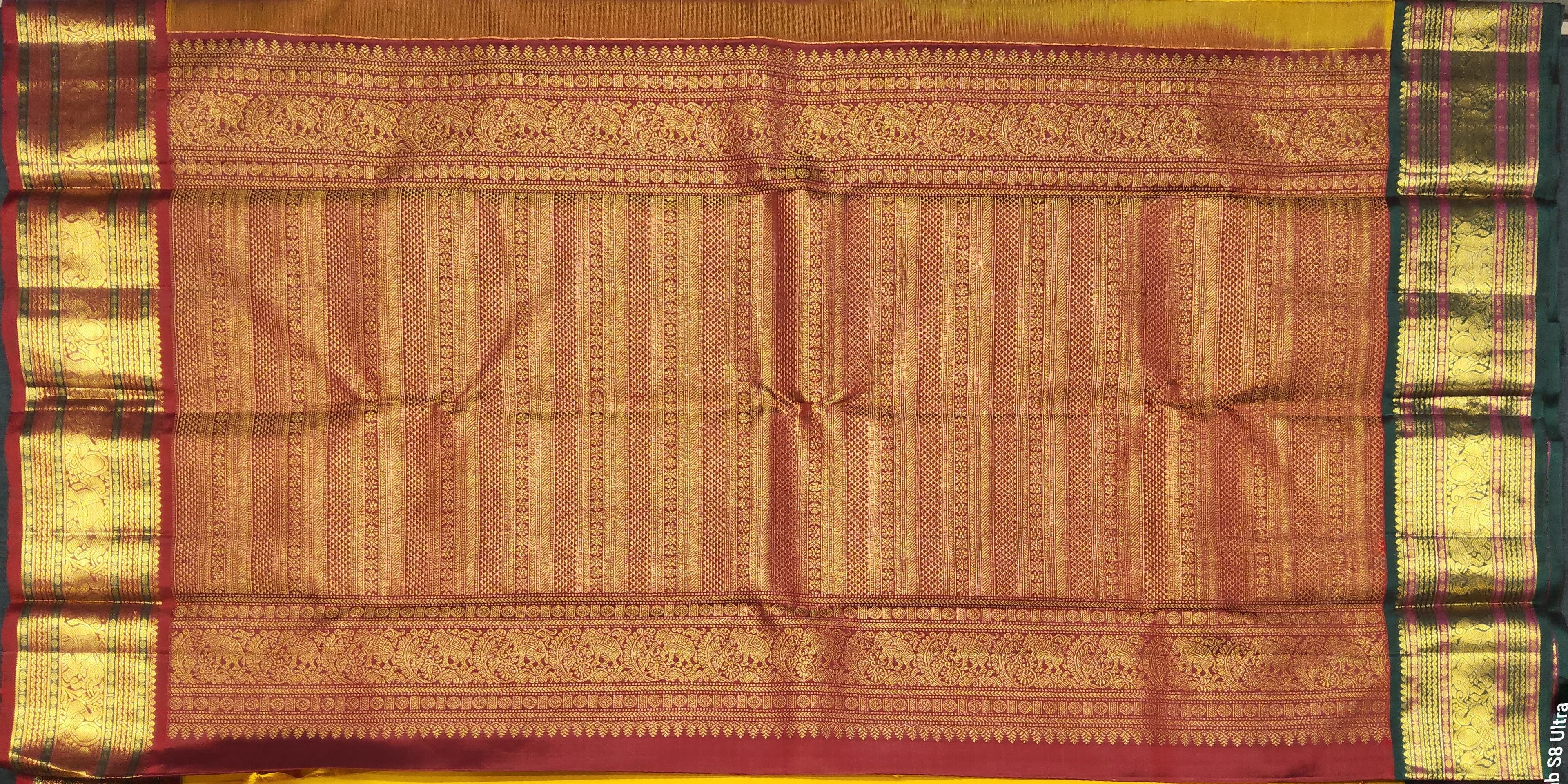 Close-up of Maroon border on Mustard Kanchipuram Saree. Authentic silk elephant and peacock motifs.